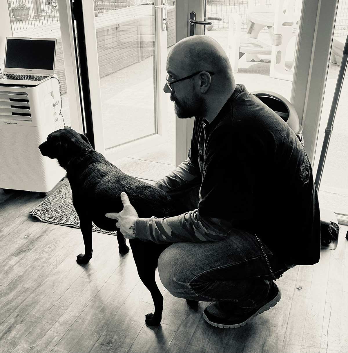 Alistair - owner of the Pawpad Dog Grooming holding black dog